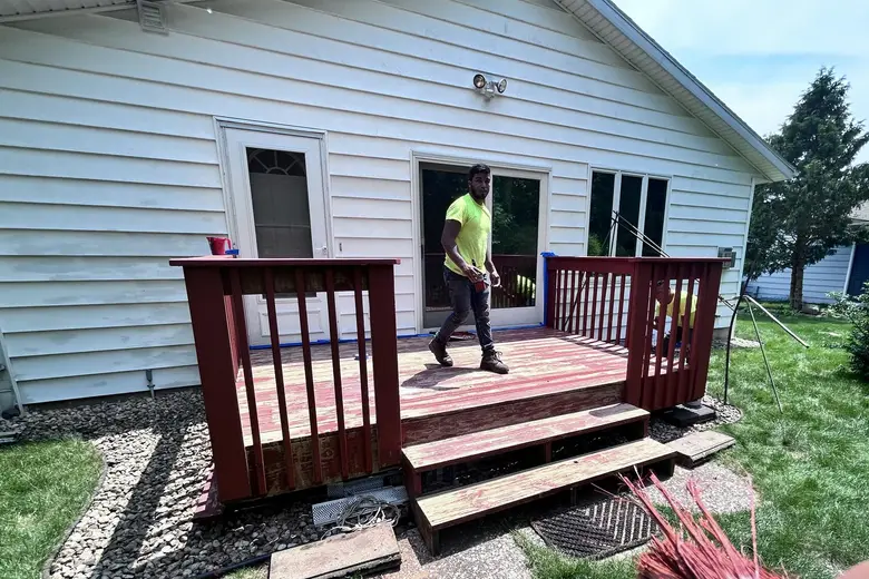 E&P crew on a worn red deck, mid-job, a stain brush in the foreground